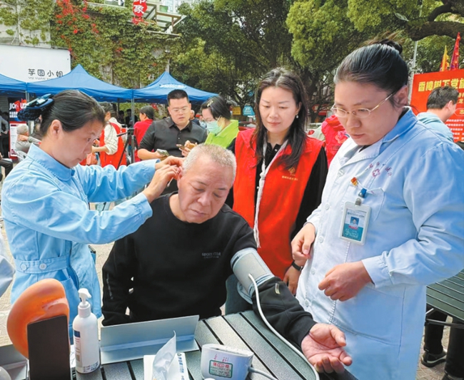 新羅區西城街道西平社區聯同龍岩市中醫院在職黨員在香樟樹下為居民義診