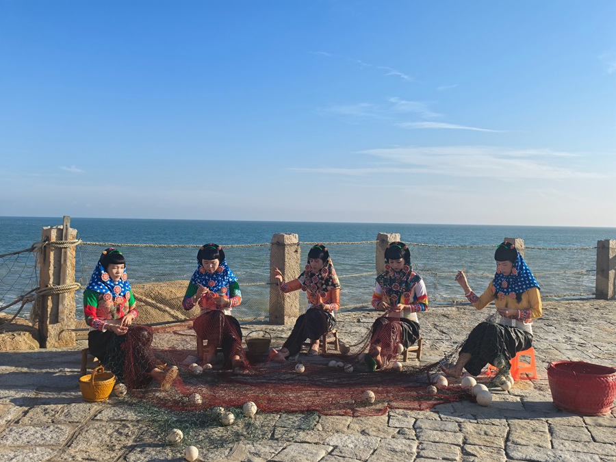 身著傳統服飾的惠安女在海邊補漁網。劉曉宇攝