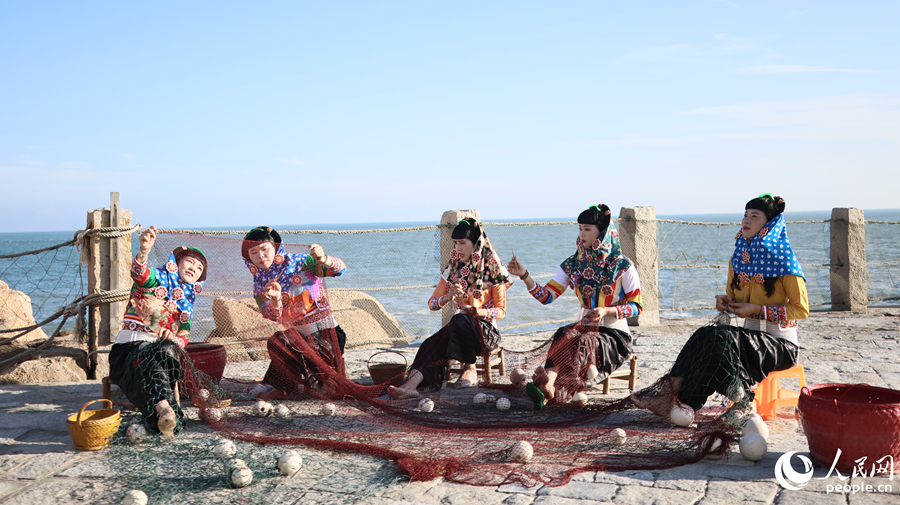 身着特色传统服饰的惠安女模特队，在海边修补渔网。人民网记者 李昌乾摄