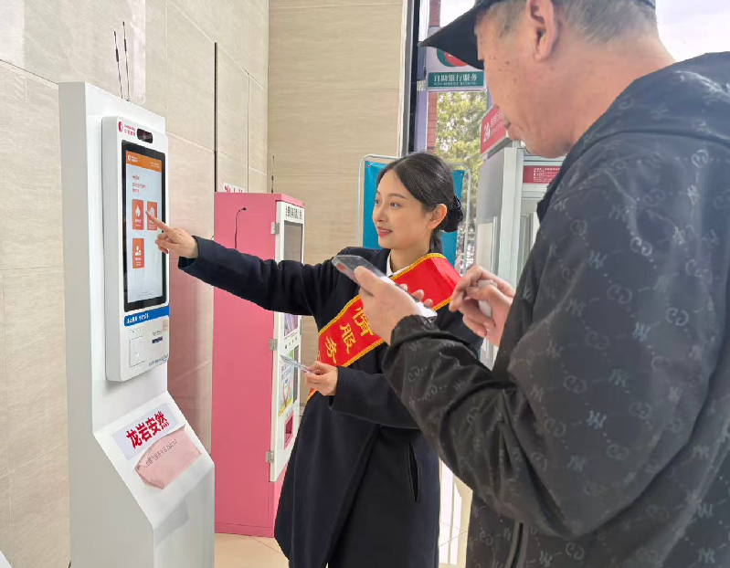 工作人員指引辦事群眾通過自助服務設備辦理業務