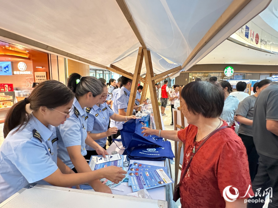 主题摊位前，工作人员正在发放宣传材料。人民网记者 张萌摄