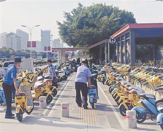 执法人员及时将地铁口乱停放共享电动车归位。(本组图/集美城管 提供)