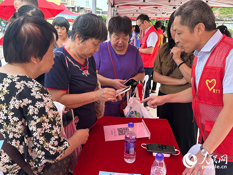 社保“宣”锋队队员为市民介绍服务。人民网记者 张萌摄