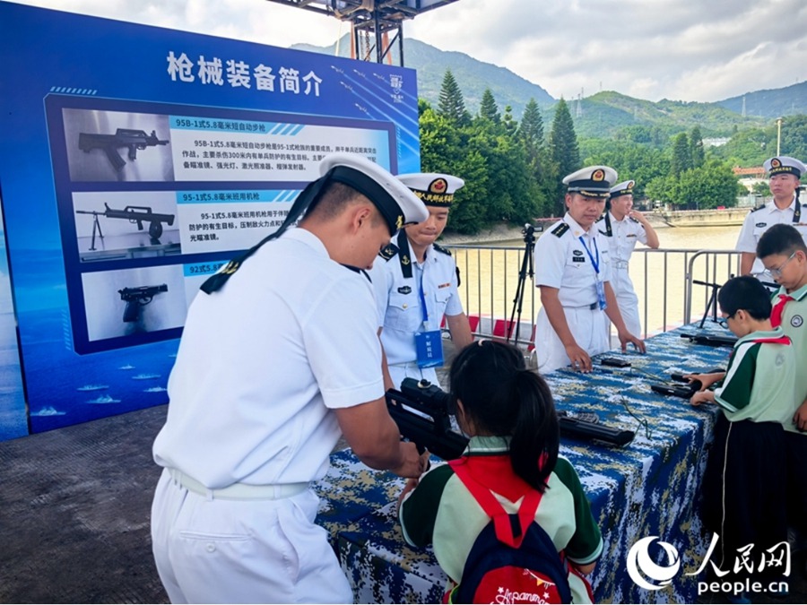 码头活动区域，海军官兵带着参观的小朋友们体验枪械装备。人民网 夏忻瑶摄