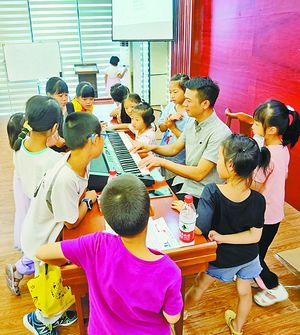 声乐培训老师兰新龙把自己家的电钢琴搬到课堂给小学员们上课。